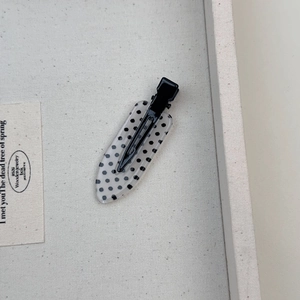 Dettaglio di un fermaglio per capelli a pois bianchi e neri su espositore beige
