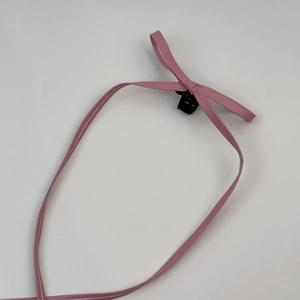 Détail d'un nœud en cuir rose avec une petite pince à griffes en plastique noir robuste