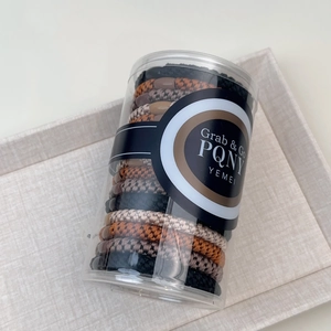 Close-up of woven high-elastic hair ties in neutral tones stored in a clear jar