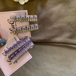 Close-up of elegant purple and champagne baguette-cut crystal hair clips on a soft knit fabric