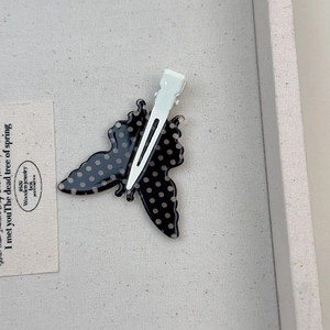 Dettaglio del fermaglio per capelli a farfalla a pois bianchi e neri con clip in metallo bianco