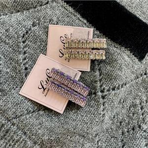 Close-up of elegant purple and champagne crystal duckbill clips on a pink display card