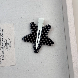 Dettaglio di un fermaglio a stella a pois neri riposto in un portagioie grigio strutturato