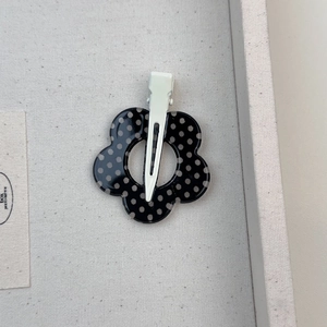 Dettaglio del fermaglio per capelli a fiore a pois bianchi e neri con clip in metallo