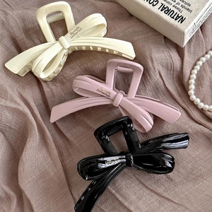Lot de 3 pinces à cheveux à nœud en crème, rose et noir sur un tissu élégant