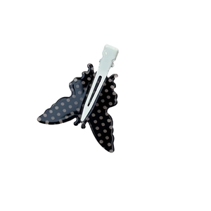 Fermaglio per capelli a farfalla con pois neri e grigi su sfondo bianco