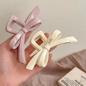 Détails de grandes pinces à cheveux avec nœud en rose poudré et crème avec logo