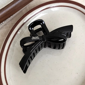 Détail d'une pince à cheveux noire brillante avec lettrage blanc Barrette LaFrance