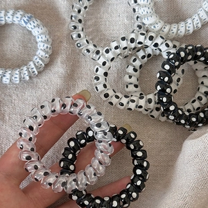Elastici per capelli a spirale con pois neri e bianchi su tessuto beige naturale