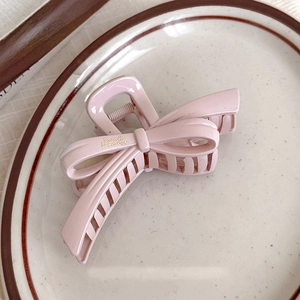 Détail d'une pince à cheveux rose en forme de nœud avec lettrage français sur une assiette