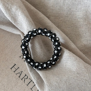 Dettaglio dell'elastico per capelli a spirale nero a pois bianchi ad alta elasticità
