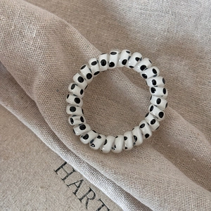 Dettaglio dell'elastico a spirale bianco con pois neri su tessuto di lino naturale