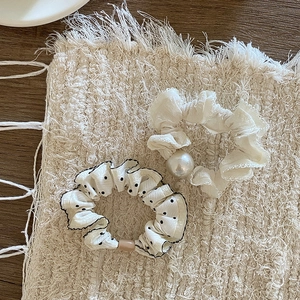 Nahaufnahme von gepunkteten und Perlen-Haargummis auf gestricktem Hintergrund
