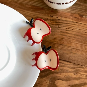 Close-up of sweet red apple-shaped hair claws with seeds detail on a white ceramic plate