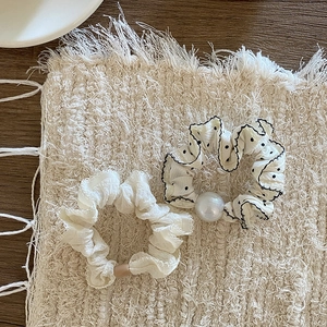 Detail von weißem Rüschen-Haargummi und gepunktetem Haarreif mit Perle auf einer Matte