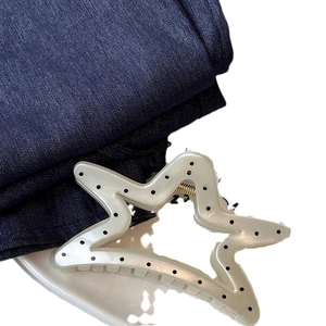Eleganter cremefarbener Stern-Haarclip mit schwarzen Punkten auf blauem Denim