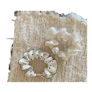 Haargummis-Set mit Polka Dots und Perlen auf einem beigen Stoffhintergrund