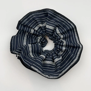 Detailed close-up of striped navy blue fabric scrunchie with soft pleated texture