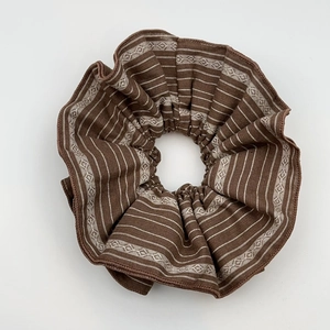 Detail of brown striped fabric scrunchie with jacquard texture and elastic pleats