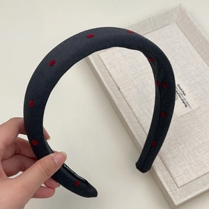 Close-up of handmade dark grey fabric headband with red polka dots and interior label