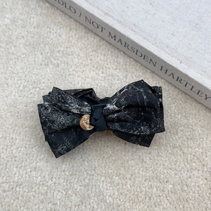 Elegant Chinese ink style bow hair clip with golden metallic detail on soft plush background
