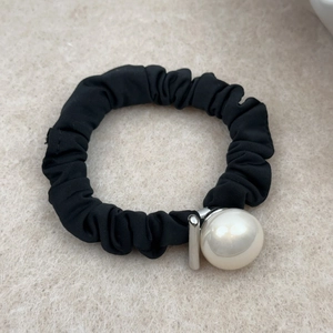 Close-up of minimalist black fabric hair tie featuring a large elegant white pearl accent