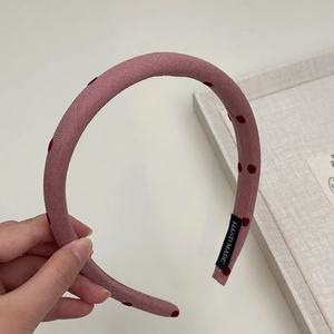 Detailed view of pink polka dot sponge headband with handmade label and textured fabric