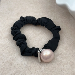 Detail of high-elastic black hair scrunchie with pink faux pearl and engraved metal bar
