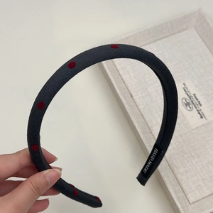Close-up of black fabric headband with red polka dots and hand made label detail