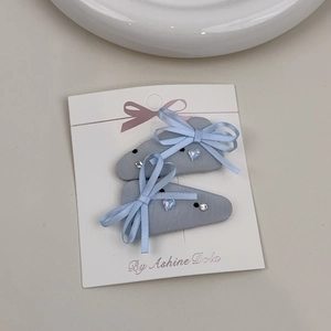 Detail of light blue ribbon bow hair clips with crystal heart beads on a display card