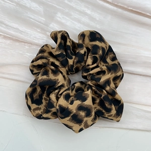 Close-up of leopard print hair scrunchie with soft fabric texture and pleated design