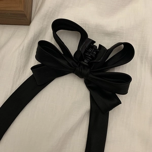 Elegant black satin ribbon bow hair claw clip for women on a clean white fabric backdrop