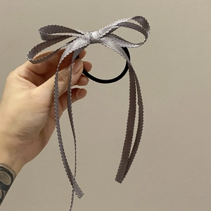 Dettaglio dell'elastico per capelli con fiocco in nastro lilla e bordi in pizzo satinato
