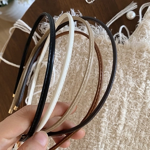 Close-up of minimalist thin PU leather headbands with fine stitching and metal end caps