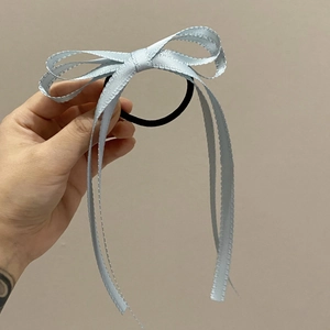 Dettaglio dell'elastico per capelli in raso azzurro con fiocco e nastri lunghi