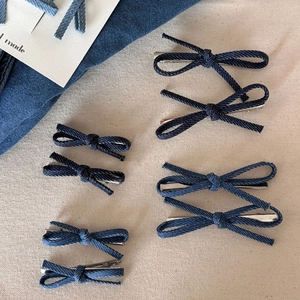 Set van 6 marineblauwe denim strik haarspelden op een getextureerde beige achtergrond
