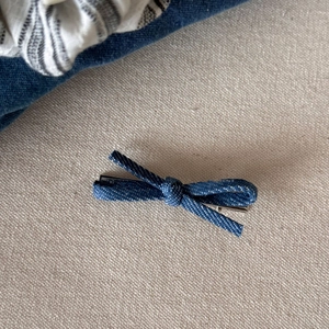 Detail van de blauwe denim strik haarclip met zilveren metalen klem op stoffen ondergrond