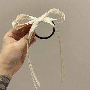 Dettaglio dell'elastico per capelli con fiocco in pizzo crema e lunghi nastri