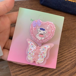 Détail de la pince cœur rose et de la barrette papillon florale sur carte