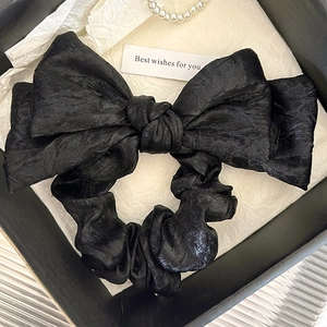 Gros plan du chouchou nœud en tissu plissé noir dans un coffret cadeau élégant