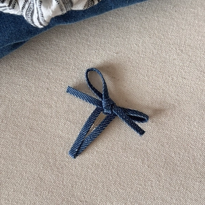 Detailopname van handgemaakte donkerblauwe denim strik met zilveren metalen haarspeld