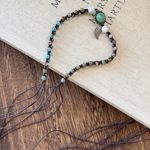 Macro detail of Bohemian braided headband featuring turquoise beads and leaf pendant charm