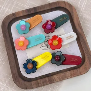 Set of six colorful acetate flower hair clips with handmade gold lettering on a tray