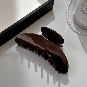 Detailed view of glossy dark brown acetate hair claw clip with strong interlaced teeth