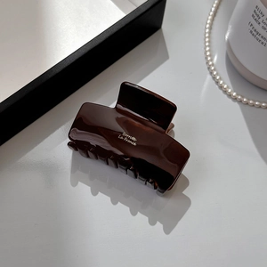 Close-up of a glossy dark brown acetate hair claw clip with Barrette La France text