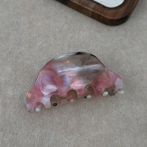 Detail view of pink marbled acetate hair claw clip showing natural texture and teeth