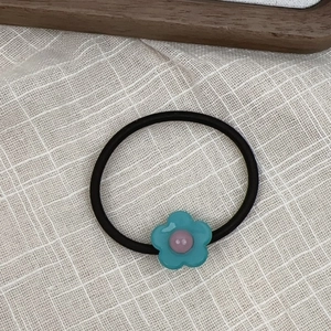 Close-up of black high-elastic hair tie with a blue acetate flower and pink center