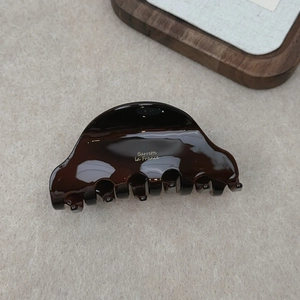 Detailed close-up of dark brown tortoiseshell acetate hair claw with golden La France logo