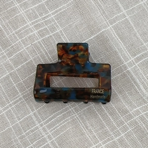 Detail of tortoise shell acetate claw clip with rectangle hollow design and gold logo