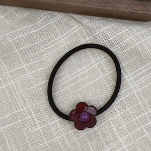 Close-up of a floral acetate charm on a high-elastic black hair tie for stylish ponytails